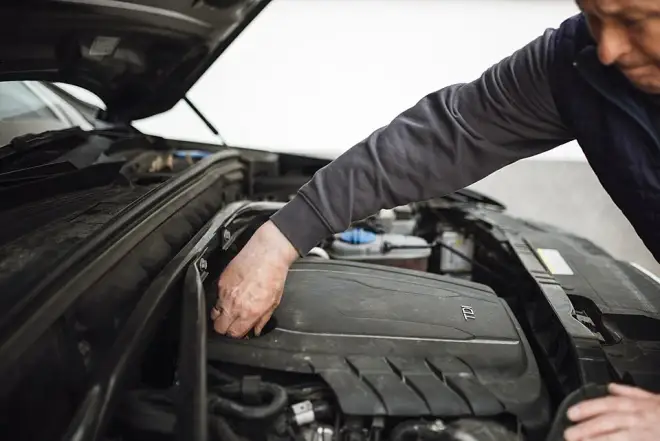Auto mechanic servicing a car engine — real photograph