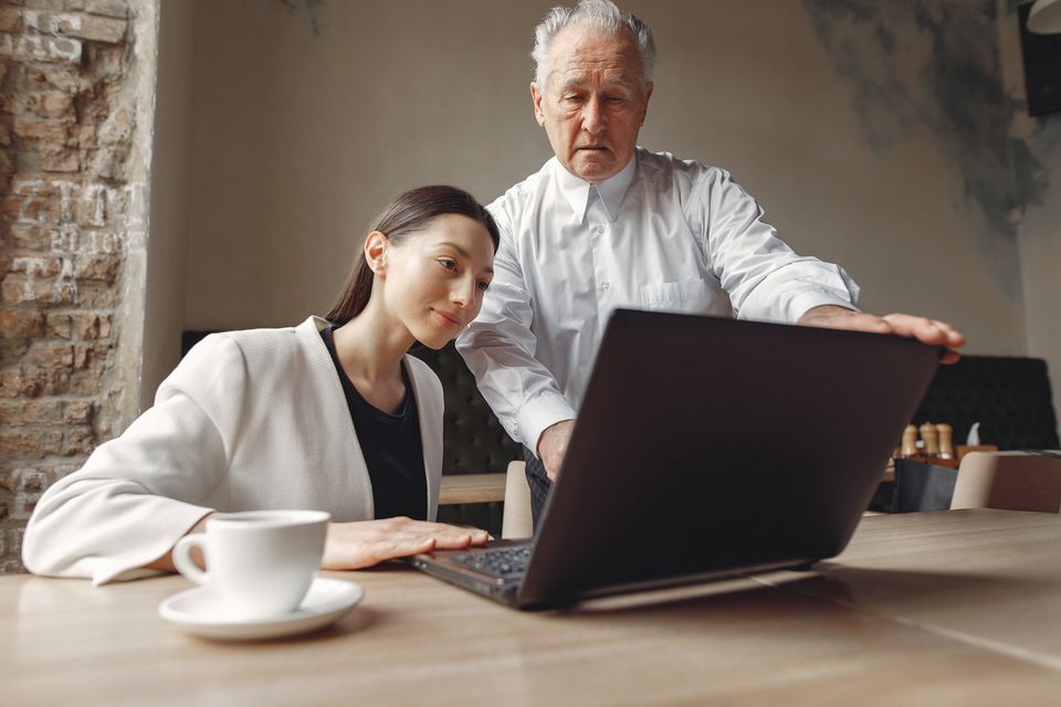 Colleagues discussing work together at a laptop — illustrative real photograph